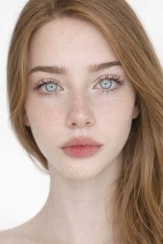 Close-up portrait of a person with red hair, blue eyes, and freckles