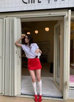 Woman in a red skirt and white t-shirt standing at a cafe entrance