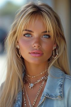 Woman with blonde hair and blue eyes wearing a denim jacket and layered necklaces