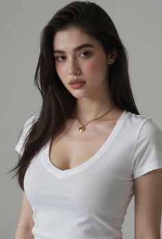 Woman with long dark hair wearing a white v-neck t-shirt and gold heart necklace
