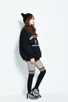 Woman in a black beanie, oversized sweatshirt, fishnet stockings, and sneakers