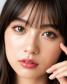 Close up portrait of a woman with dark hair and bangs, wearing pink lipstick