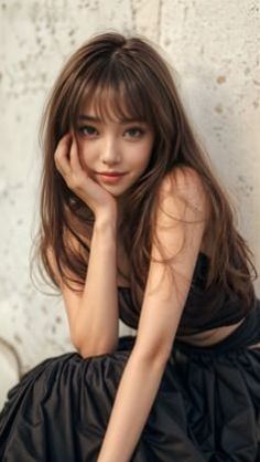 Woman with long brown hair and bangs wearing a black top and skirt