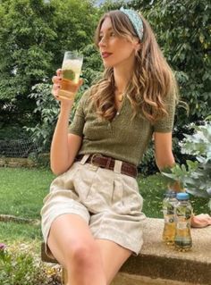Woman with long hair and a headband holding a drink in a garden