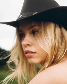 Blonde woman wearing a cowboy hat outdoors, looking to the side