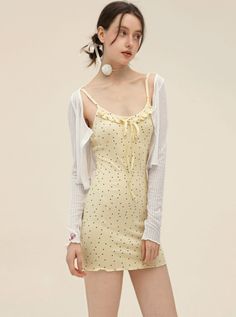 Woman in a yellow polka dot dress and white cardigan with a choker