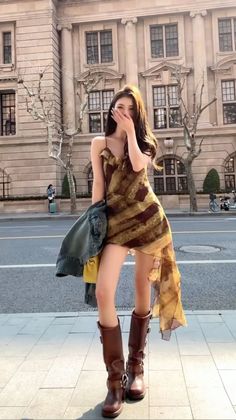 Woman in a patterned dress and brown boots on a city street
