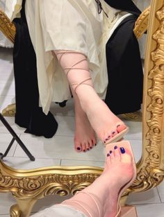 Person's bare feet and sandals reflected in an ornate gold mirror
