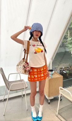 Young woman in a bucket hat, crop top, and mini skirt posing indoors