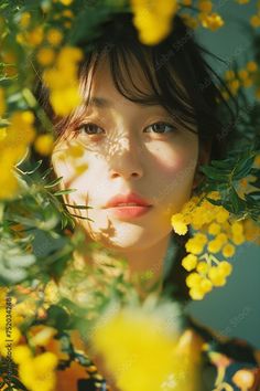 Woman with short hair surrounded by yellow flowers and dappled sunlight
