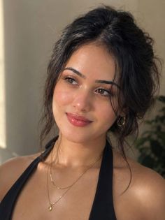 Woman with dark hair wearing a black halter top and gold jewelry