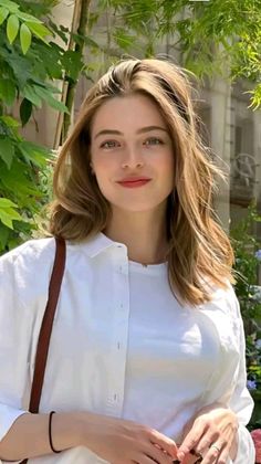 Woman with long brown hair wearing a white shirt outdoors