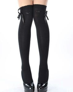 Legs wearing black thigh-high socks with ribbon bows and platform heels