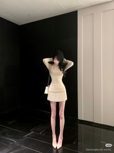 Woman in a beige mini dress and high heels posing indoors