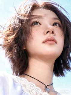 Woman with short brown hair and freckles looking up against a bright blue sky
