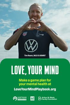 Man with a beard and man bun making a heart shape with his hands