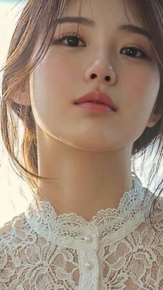 Close up portrait of a woman wearing a white lace top with pearl buttons