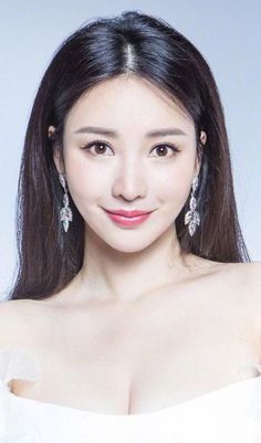 Woman with long black hair and earrings wearing a white dress with cleavage