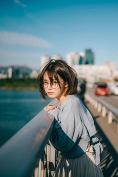 Woman with short hair and glasses leaning on a railing during golden hour