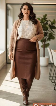 Woman in a long cardigan, brown skirt, and boots standing indoors