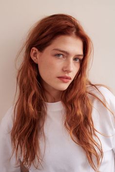 Woman with long red hair and freckles wearing a white t-shirt