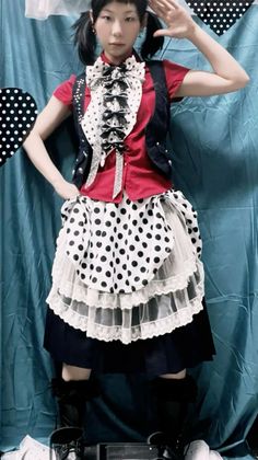 Person in a polka dot and ruffled outfit with pigtails posing indoors