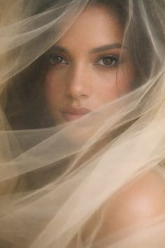 Woman with brown eyes looking through sheer fabric with soft lighting