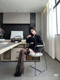 Woman in a black blazer, crop top, and mini skirt with thigh-high stockings in an office