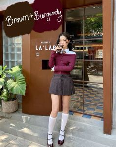 Woman in a pleated skirt and off-shoulder top drinking from a cup outdoors