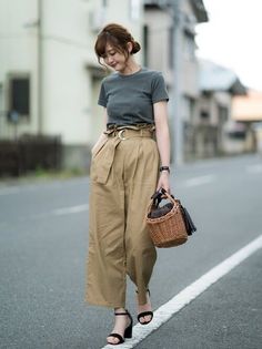 Woman in a grey t-shirt and paper bag pants walking on a street