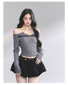 Woman with long dark hair wearing a crop top and mini skirt in a studio