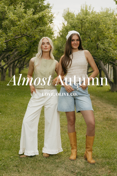 Two women posing in an orchard with green trees and grass