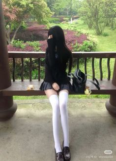 Person in a school uniform and white thigh highs sitting on a bench outdoors