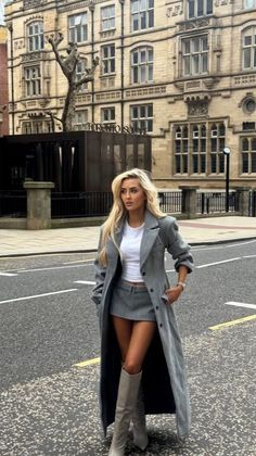 Woman with long blonde hair in a gray coat and mini skirt on a city street