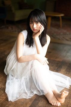 Woman in a white dress sitting on a wooden floor with soft lighting
