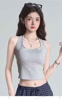 Woman with long hair wearing a gray tank top and plaid shorts, sunglasses on head