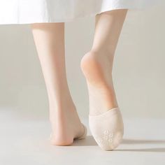 Person wearing a white dress and no-show socks, standing on a light surface