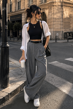 Woman in a black crop top and grey wide-leg pants on a city street