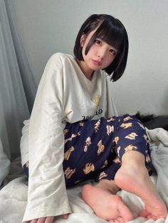 Woman with short black hair wearing teddy bear print pajama pants indoors