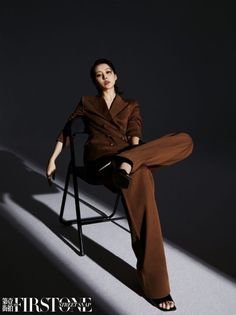 Woman in a brown suit sitting on a chair with dramatic lighting