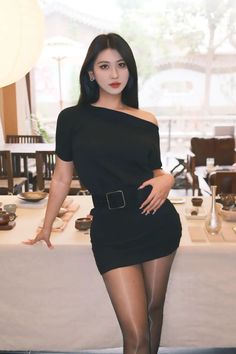 Woman in a black off-shoulder dress and pantyhose posing in a restaurant