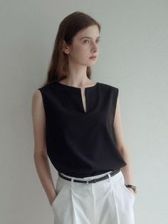 Woman with long hair wearing a black top and white pants indoors