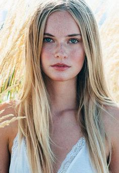 Woman with blonde hair and freckles in a white top outdoors