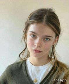 Young woman with blue eyes and long hair wearing a green cardigan and white t-shirt