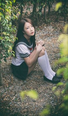Young woman in a school uniform sitting on the ground outdoors