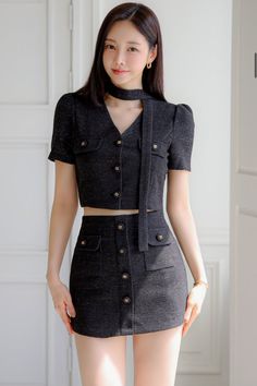 Woman in a black cropped top and mini skirt with a choker and gold earrings