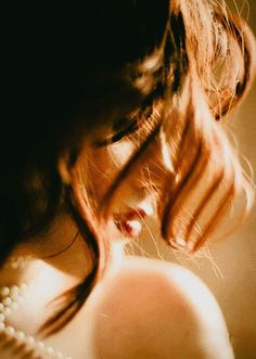 Woman with red hair and a pearl necklace, soft lighting and warm tones
