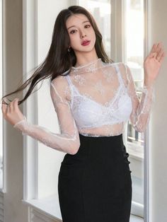 Woman in a white lace top and black skirt posing indoors