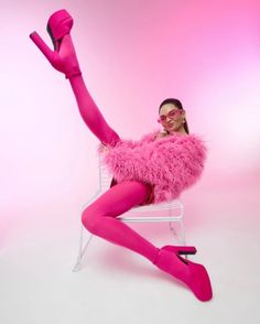 Woman in a vibrant pink furry jacket and tights striking a playful pose