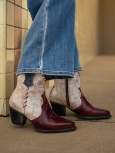 Person wearing two-tone cowboy ankle boots and blue flared jeans outdoors